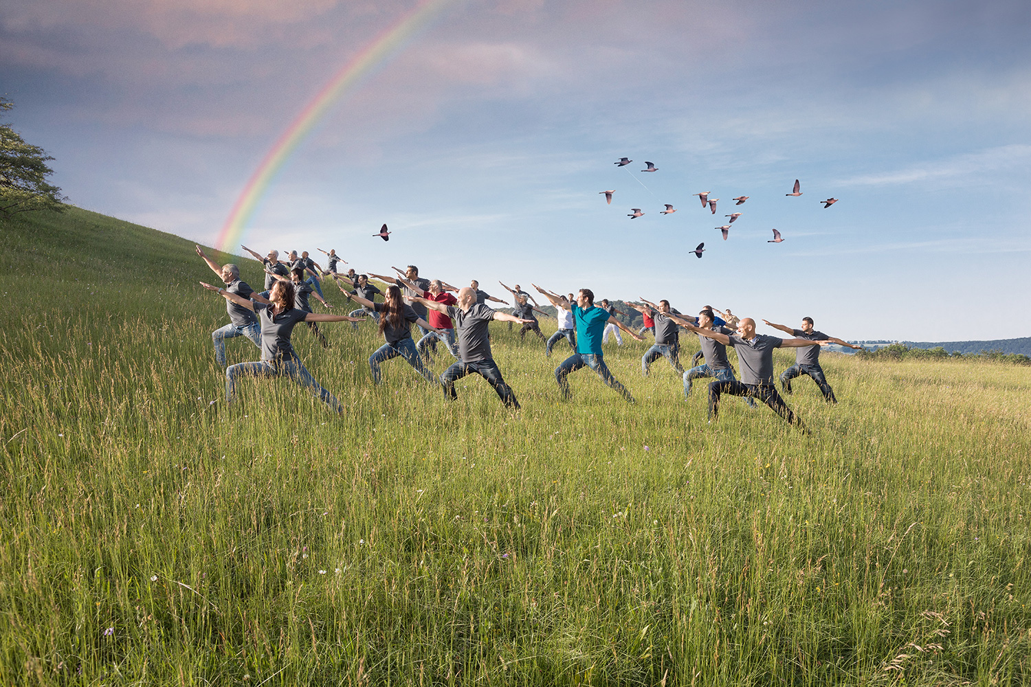 L'équipe du MBA dans une pose méditative dans la nature avec un arc-en-ciel dans le ciel