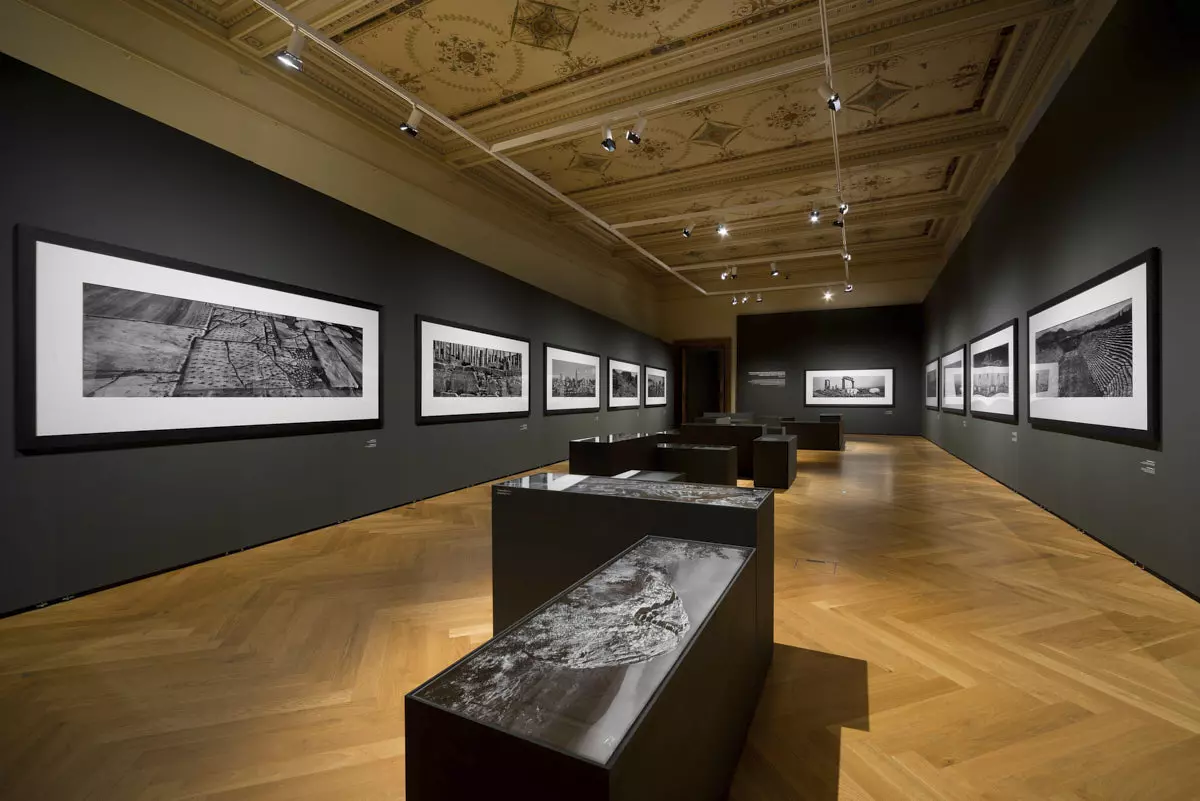 Großformatige Schwarzweiß-Fotografien an dunklen Mila-wall Wänden im Kunstgewerbemuseum Prag, davor dunkle Vitrinen